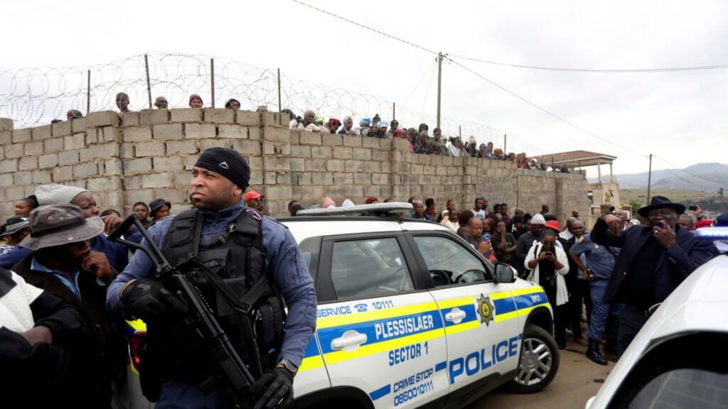 Curious onlookers behind a police cordon, where ten people from the same family were shot dead Friday, April 21, 2023.